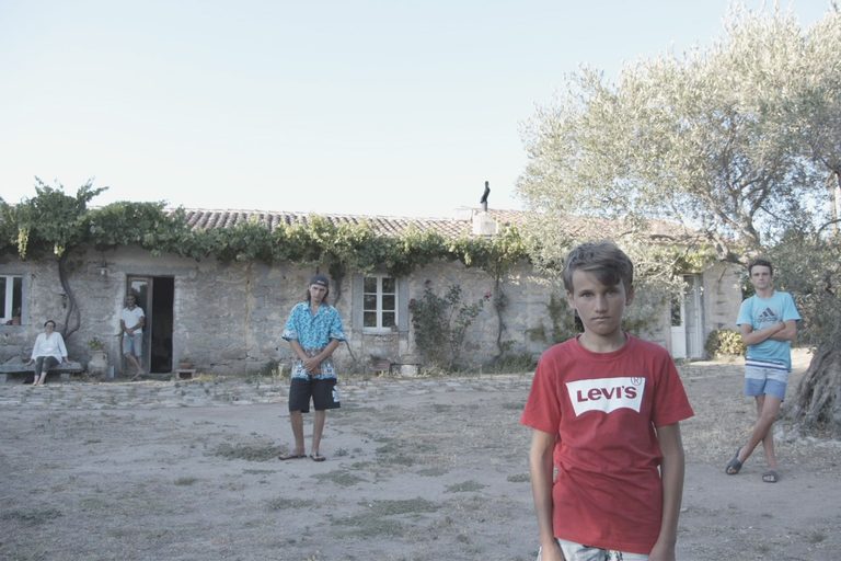 ritratto di una famiglia davanti a uno stazzo della gallura, con tre giovani ragazzi disposti a distanza tra di loro e i genitori sullo sfondo vicino all'uscio di casa